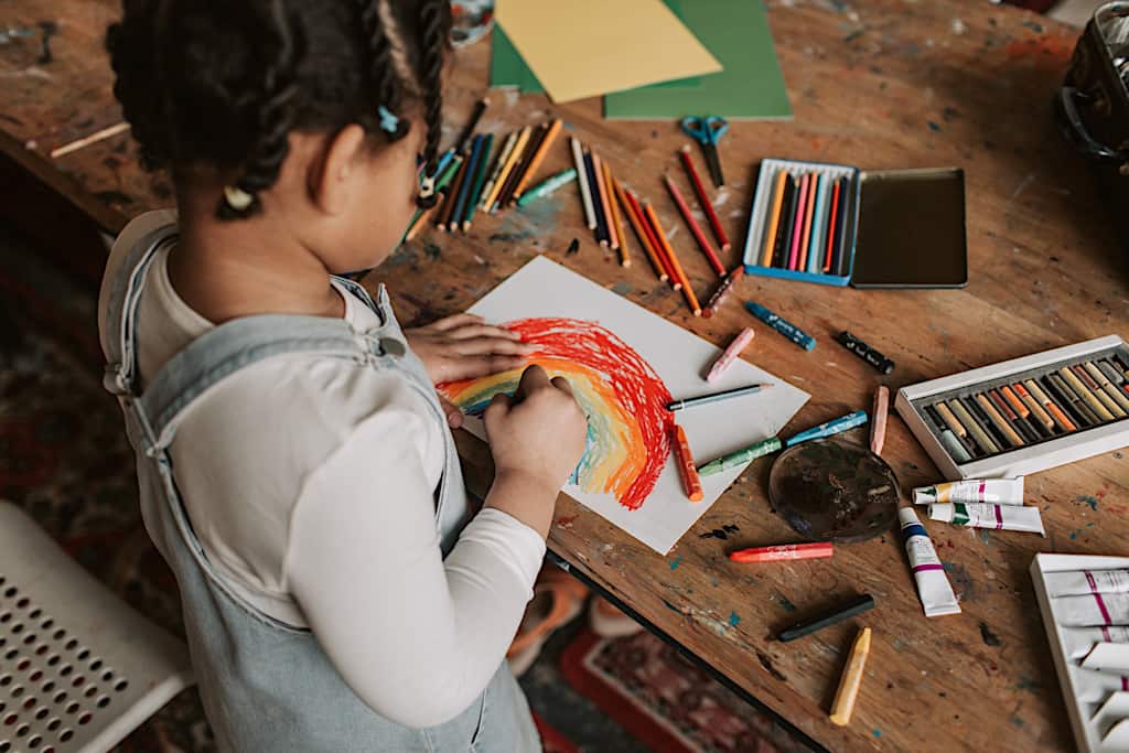 Vis et Deviens - un enfant dessinant sur une feuille blanche avec plusieurs feutres.