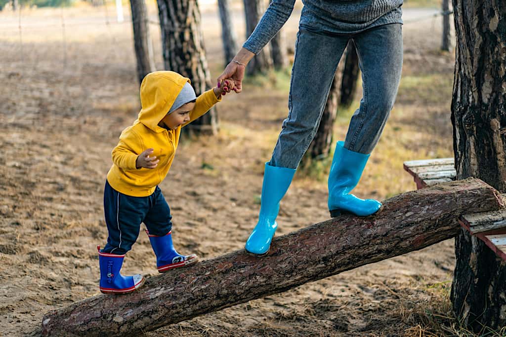 Vis et Deviens - Un bénévole qui aide un enfant à grimper sur un tronc d'arbre