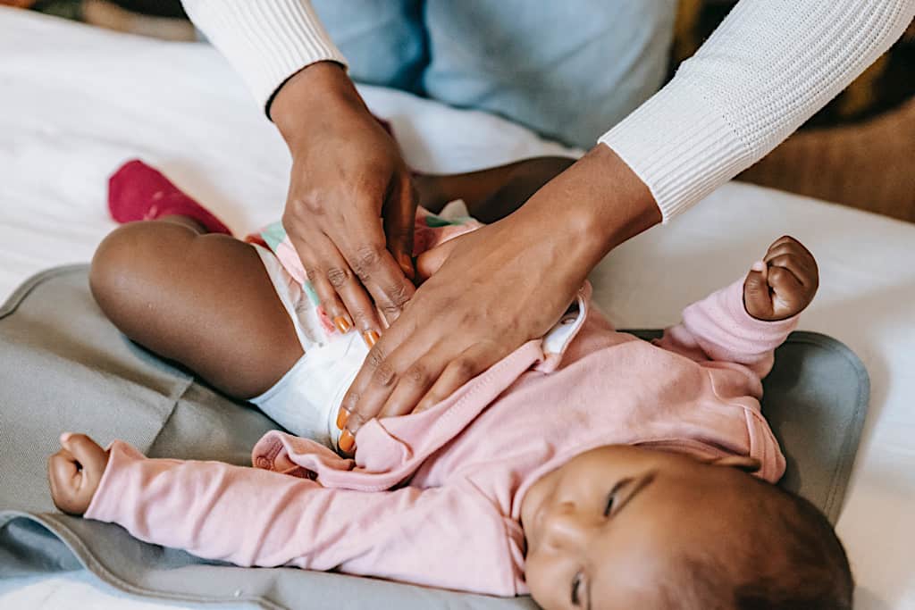 Vis et Deviens - Bébé allongé sur un lit et une bénévole qui le change